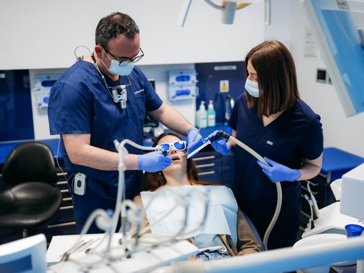 Dr Dantsis and a dental nurse at London Smile Studio carry out a tooth extraction on a patient at the chairside.